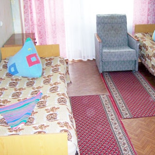 На фото: комната с окном, две кровати, прикроватная тумбочка, кресло